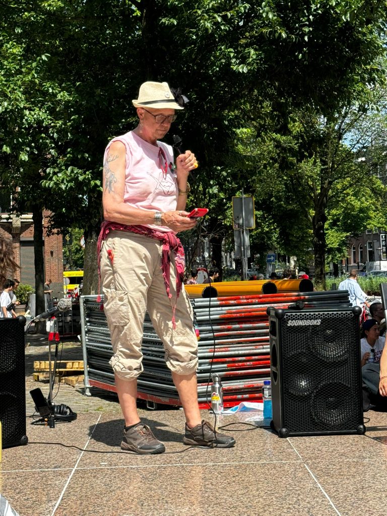 vreer in e pink shirt and ligth hat end traousers reading their speech at the Homomonument in Amsterdam